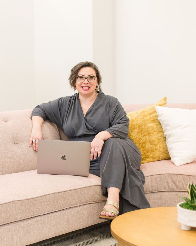 Racheal smiling on couch with open laptop